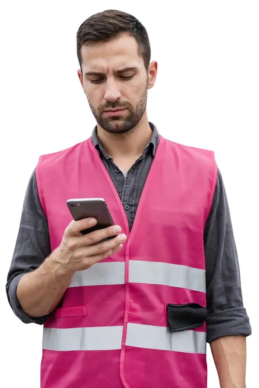 Ein Lagerteamleiter in einer Warnweste liest eine Nachricht auf seinem Smartphone.